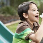 Boy using asthma inhaler in the garden